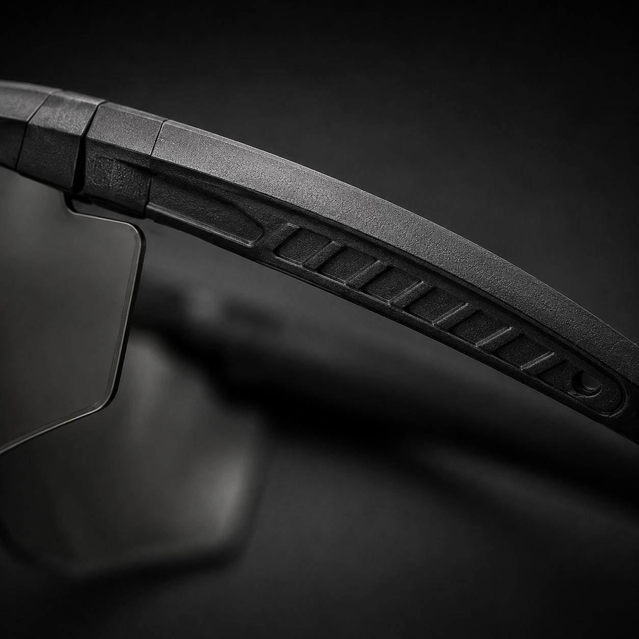 Close-up of tactical goggles temple arm texture, black frame, showing anti-slip details, transparent lenses, adjustable nose pad, protective eyewear for CS and outdoor use.